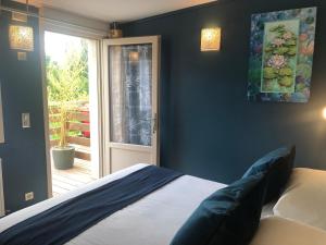 ein Schlafzimmer mit einem Bett und einer Glasschiebetür in der Unterkunft Logis Hôtels Troglododo in Azay-le-Rideau