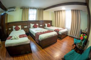 a bedroom with two beds and a couch and a chair at Hotel Yambu in Kathmandu