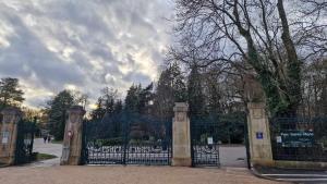 a gate in a park with trees and a cloudy sky at Cocon sous les toits By UnSejourANancy Fr in Nancy