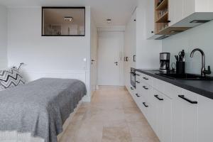 a white kitchen with a bed and a sink at App Nordseeperle in List