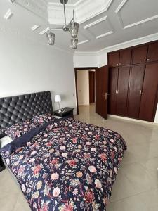 a bedroom with a large bed with a floral blanket at Tanger lovely apart only family in Tangier