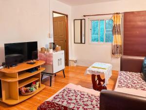 a living room with a couch and a television at Ao Luek Homie Homestay in Krabi town