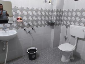 a man taking a picture of a bathroom with a toilet and sink at Hotel Lilac Doors in Patna +24 photos