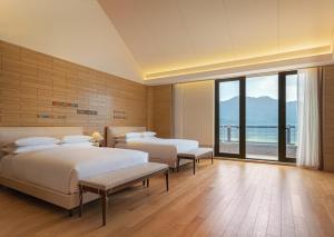 a bedroom with two beds and a large window at Conrad Hangzhou Tonglu in Yinzhu