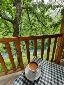 Šćepan-PoljeにあるRafting Camp Modra Rijekaのポーチのテーブルに座ってコーヒーを飲む