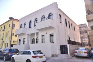 ein weißes Gebäude mit davor geparkt in der Unterkunft Yona 8 in Tel Aviv