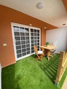 a room with a table and chairs and green grass at El Olivar Caleta Mar in Caleta De Fuste