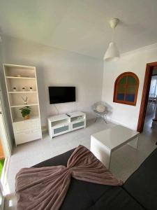 a living room with a couch and a flat screen tv at El Olivar Caleta Mar in Caleta De Fuste