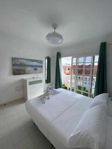 sypialnia z dużym białym łóżkiem i oknem w obiekcie El Olivar Caleta Mar w mieście Caleta De Fuste