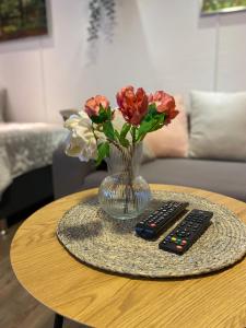 un vase de fleurs et deux télécommandes sur une table dans l'établissement Apartment Mette, à Mayen