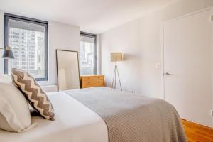 a white bedroom with a bed and two windows at Midtown 1br w doorman gym nr Times Square NYC-1208 in New York