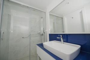 a bathroom with a white sink and a glass shower at Twin Towers Orbi City Batumi in Batumi