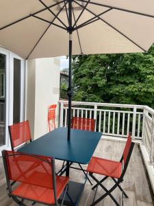 einen Tisch und Stühle mit Sonnenschirm auf der Veranda in der Unterkunft Charmant appartement de type 3 in Gujan-Mestras