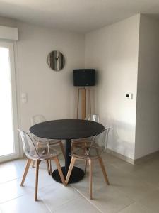 ein schwarzer Tisch und zwei Stühle in einem Zimmer in der Unterkunft Charmant appartement de type 3 in Gujan-Mestras