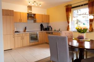 a kitchen with wooden cabinets and a table with chairs at Haus Ohragrund in Oberhof