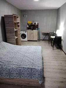 a bedroom with a bed and a table and a kitchen at A cozy bedsit! in Tashkent