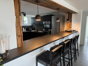 a kitchen with a bar with black cabinets and black chairs at See und Berge Garden in Faulensee