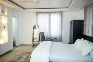 a bedroom with a large white bed and a chair at Seven Brothers Apartments in Accra