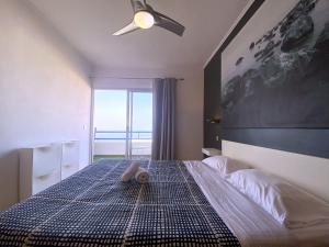 a bedroom with a bed with a ceiling fan and a window at Tropicalidays Paraiso Seafront in Playa Paraiso +34 photos