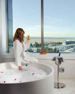 a woman sitting in a bath tub with a drink at FLY INN BAKU in Baku