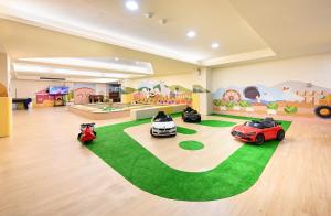 萬里的住宿－群策翡翠灣溫泉飯店，一间有三辆玩具车的房间,铺在绿色地毯上