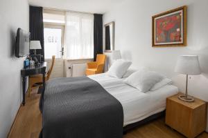Schlafzimmer mit einem Bett, einem Schreibtisch und einem TV in der Unterkunft Strandhotel Domburg in Domburg
