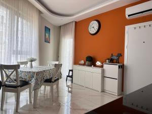 a dining room with a table and a clock on the wall at Cozy 2-Bedroom Apartment, Cleopatra Beach, Alanya in Alanya