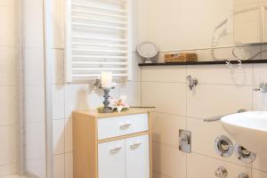 a bathroom with a sink and a candle on a cabinet at Haus Ohragrund in Oberhof +70 photos
