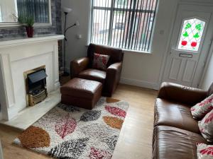 a living room with two leather chairs and a fireplace at Aldbrough Cottage in Aldbrough