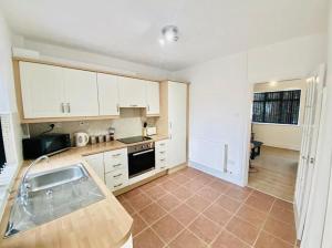 a kitchen with white cabinets and a tile floor at Aldbrough Cottage in Aldbrough