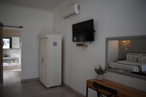 Symponia Guesthouse في Ghanzi: غرفة نوم بسرير وتلفزيون على جدار