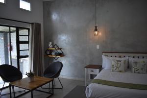 Symponia Guesthouse في Ghanzi: غرفة نوم بسرير وكرسيين وطاولة
