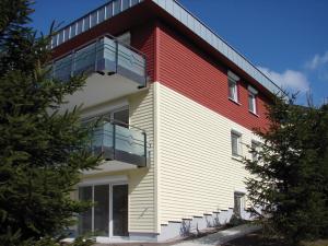a red and white building with a balcony at Haus Ohragrund in Oberhof