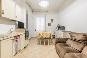 Monserrato Cozy Apartment near the Policlinico! في مونسيرّاتو: مطبخ وغرفة معيشة مع أريكة وطاولة
