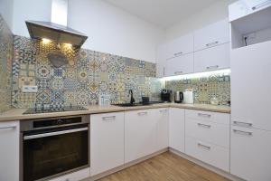 eine Küche mit weißen Schränken und einer gefliesten Wand in der Unterkunft Apartament SZMARAGDOWY z garażem Centrum Gliwic-Klimatyzacja in Gliwice