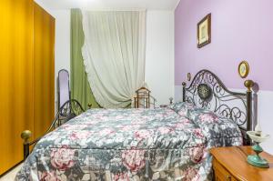 1 Schlafzimmer mit einem Bett mit Blumenbettdecke in der Unterkunft Monserrato Cozy Apartment near the Policlinico! in Monserrato