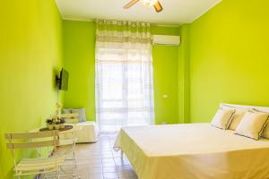 1 dormitorio con paredes verdes, 1 cama y 1 silla en Iole's home, en Giardini Naxos