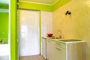 cocina con paredes verdes y puerta blanca en Iole's home, en Giardini Naxos