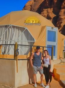 a man and a woman standing in front of a tent at Bubble Sofia Luxury Rum Camp in Wadi Rum