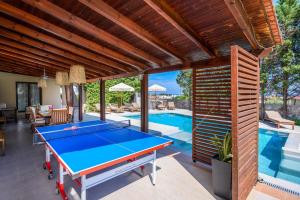 a ping pong table on a patio next to a pool at 3 Roses Residence in Afantou