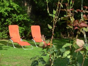 two orange chairs sitting in the grass at La Grange du Bourg in Deneuille-les-Mines +8 photos