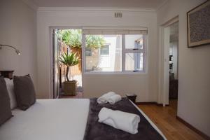 a bedroom with a bed with two towels on it at Beachside Cottage in Bloubergstrand