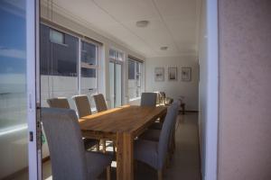 uma sala de jantar com uma mesa de madeira e cadeiras em Beachside Cottage em Bloubergstrand
