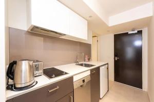 a small kitchen with a sink and a refrigerator at Well located 1Bed Unit in near Albert Park w Gym! in Melbourne