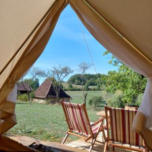 two chairs in a tent with a view of a field at Camping équipé : Vallon de Laborie in Astaillac