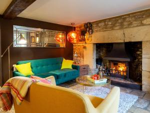a living room with a green couch and a fireplace at Betty's Cottage in Burford