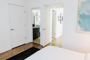 a white bedroom with white doors and a bathroom at The Vinyl at Music Row - Garden Suite in Nashville