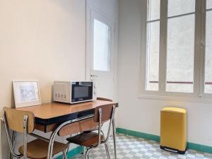 Habitación con escritorio, microondas y sillas. en Joli Appartement - Proche Gare St Charles - Les Frères de la Loc', en Marsella