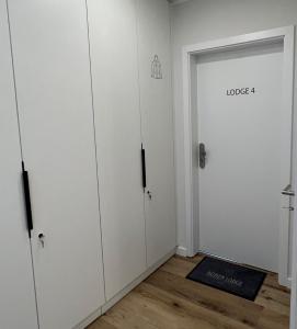 una habitación con armarios blancos y una puerta con el lodge de palabras en Dünen Lodge 4, en Juist