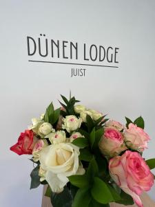 un ramo de flores en un jarrón con la palabra cena lodge en Dünen Lodge 4 en Juist